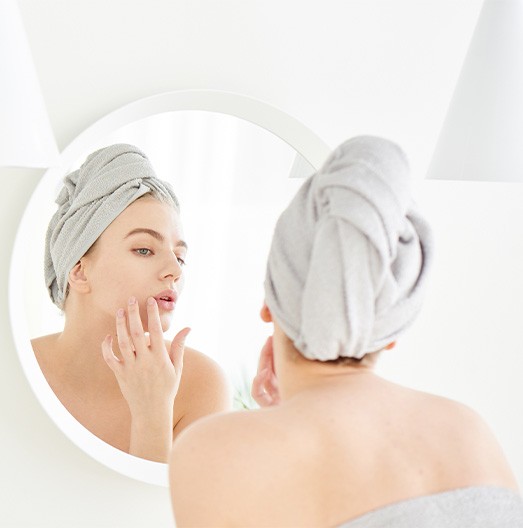 Woman looking at herself in mirror, checking for wrinkles