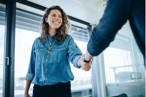 Woman smiling while shaking hands in office building