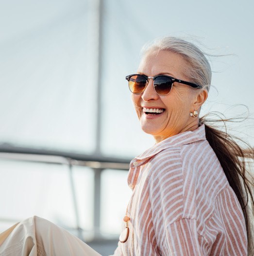 Woman with long hair in striped shirt smiling on a boat with dentures