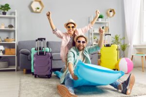Man and woman packed for summer vacation smiling in their living room