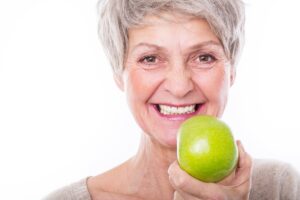 Smiling older woman holding an apple